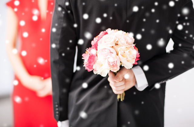 love, romance, holiday, celebration concept - man hiding bouquet of flowers behind his back